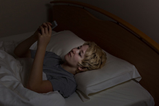 Young woman unable to sleep on cell phone in bed
